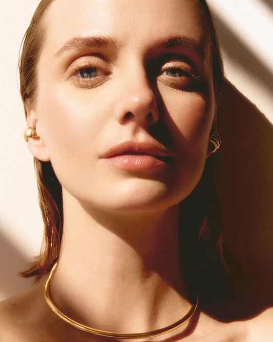 Close-up of a person wearing a gold necklace with soft lighting